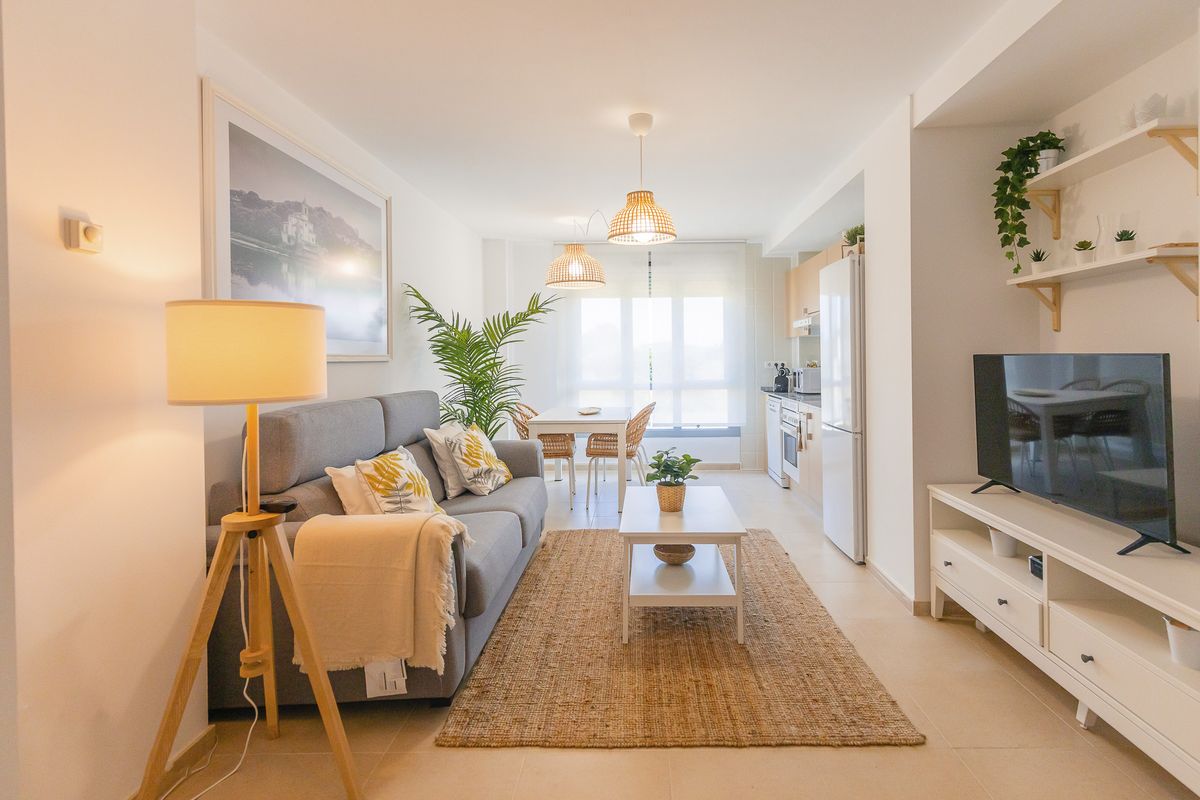 Salón-comedor del apartamento en Posada de Llanes, con sofá, mesa y cocina abierta al fondo